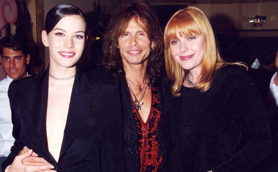 Liv Tyler, Steven Tyler and Bebe Buell posing for a photo by an event. 