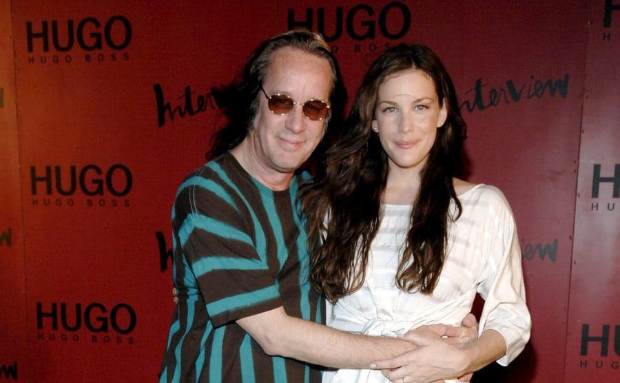 Todd Rundgren and Liv Tyler are posing on the red carpet for photos. 