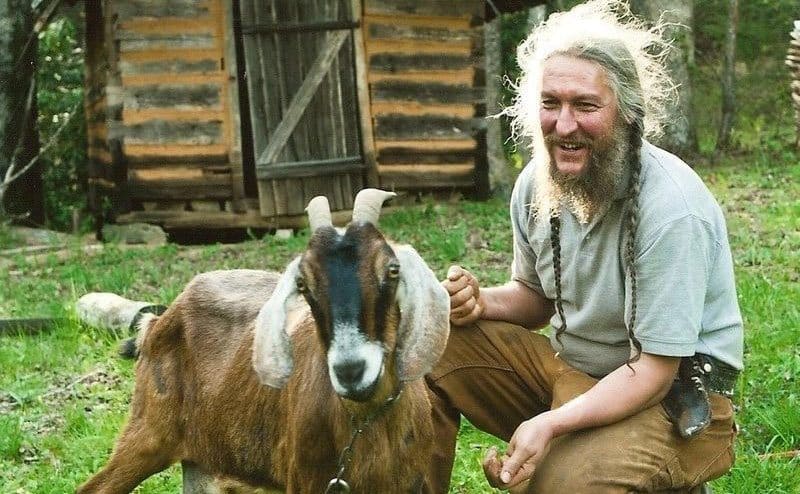 Eustace feeding a goat on his farm.