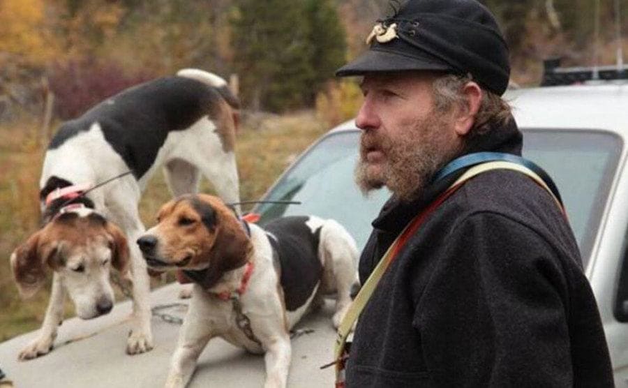 Lewis standing next to his truck with two of his dogs sitting on the hood of the truck.