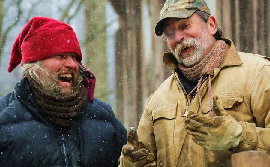 Preston Roberts and Eustace Conway are laughing out in the snow.
