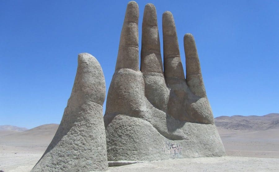 Escultura de una mano que emerge del desierto