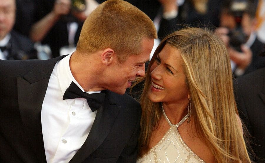 Brad Pitt and Jennifer Aniston photographed on the red carpet while smiling at each other. 