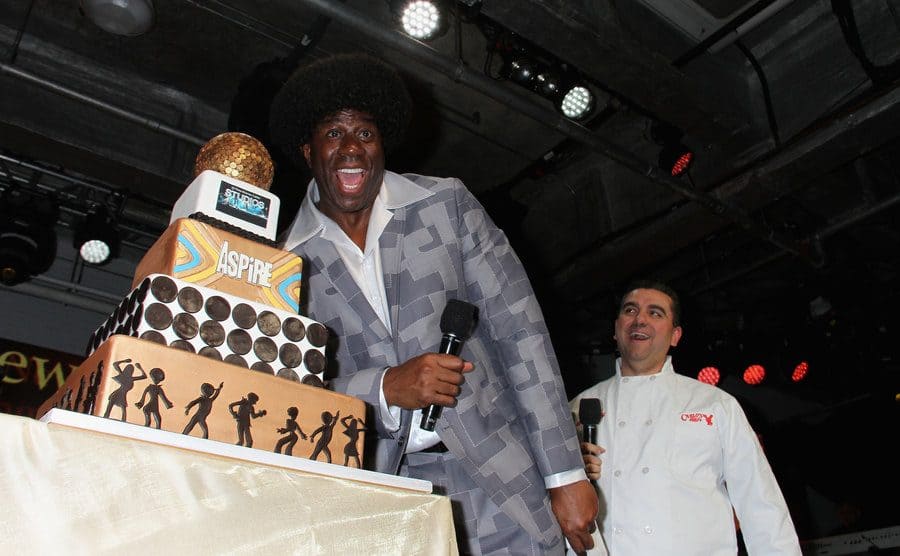 Magic Johnson standing next to a five-tiered cake which Buddy made for him 