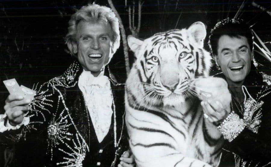 Siegfried and Roy at a casino table with a large tiger. 