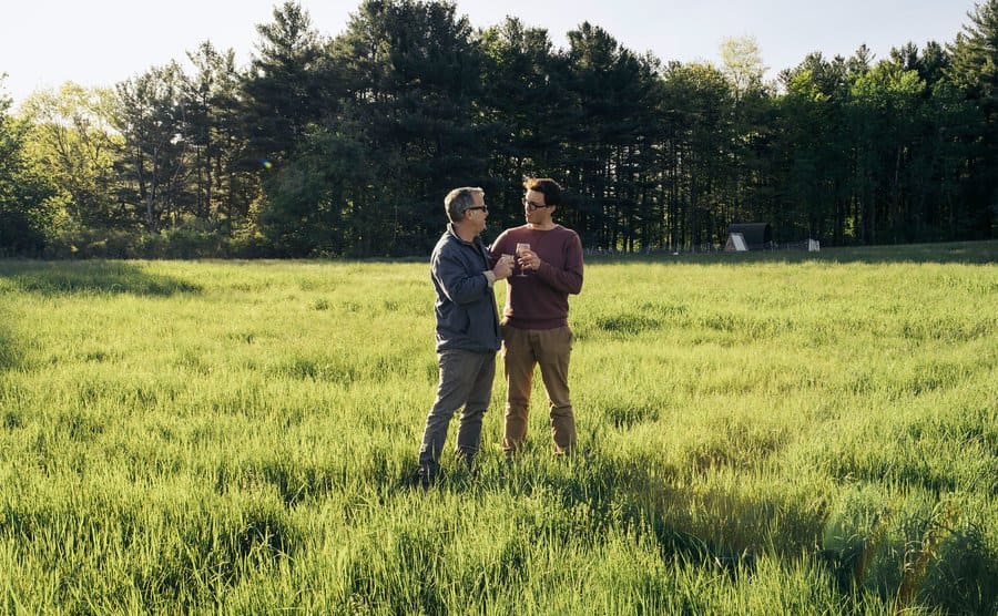 Two men enjoying discussion in a grassy field.