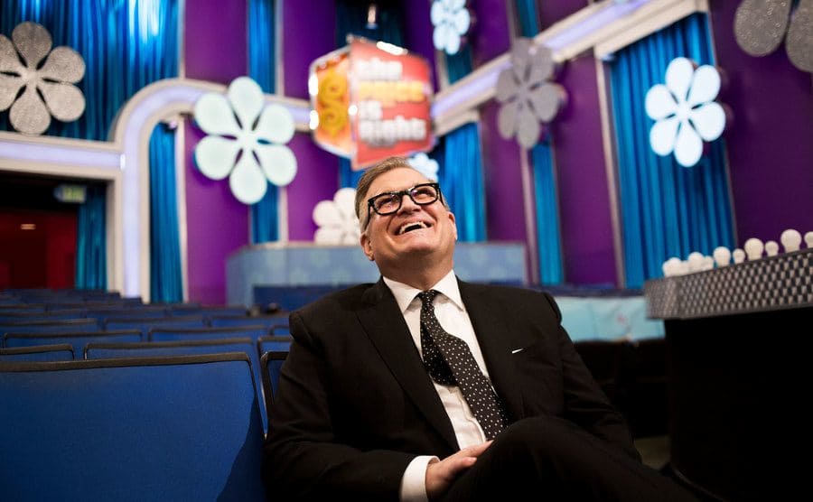 Drew Carey is sitting on a theater seat used for the show on the CBS lot in Los Angeles.