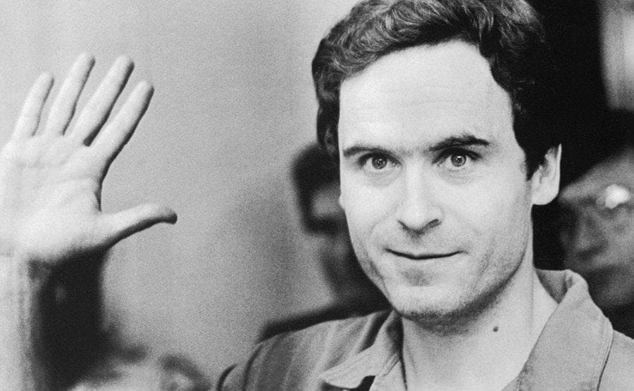 Close-up portrait of Ted Bundy waving in the court of his indictment for the murder of two women.