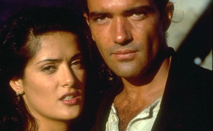 Salma Hayek and Antonio Banderas are sitting next to a bed on the floor.