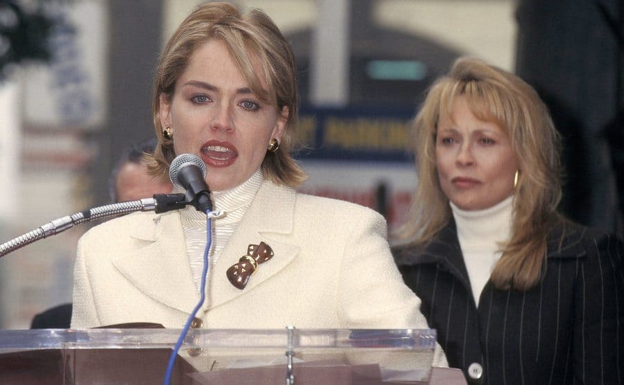 Sharon Stone is speaking at her Hollywood Walk of Fame Star Ceremony Salute while Faye Dunaway accompanies her.
