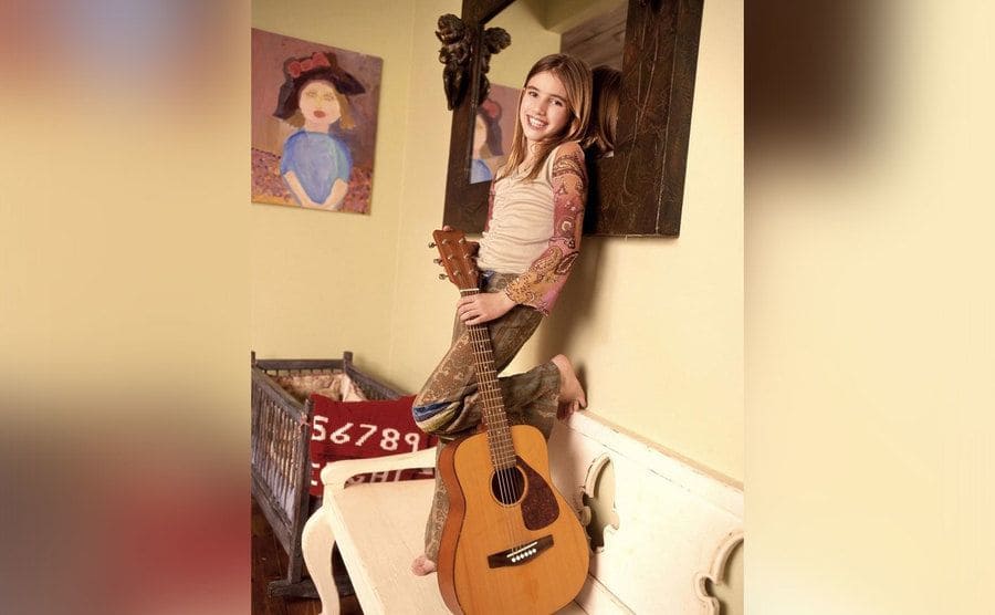 A young Emma Roberts poses with her guitar. 