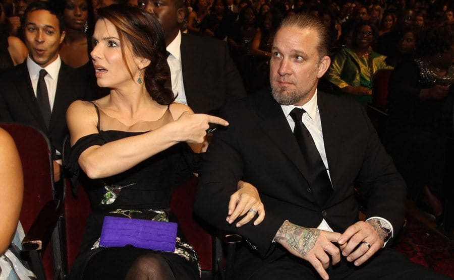 Sandra Bullock points her finger to Jesse James during an event in an auditorium. 