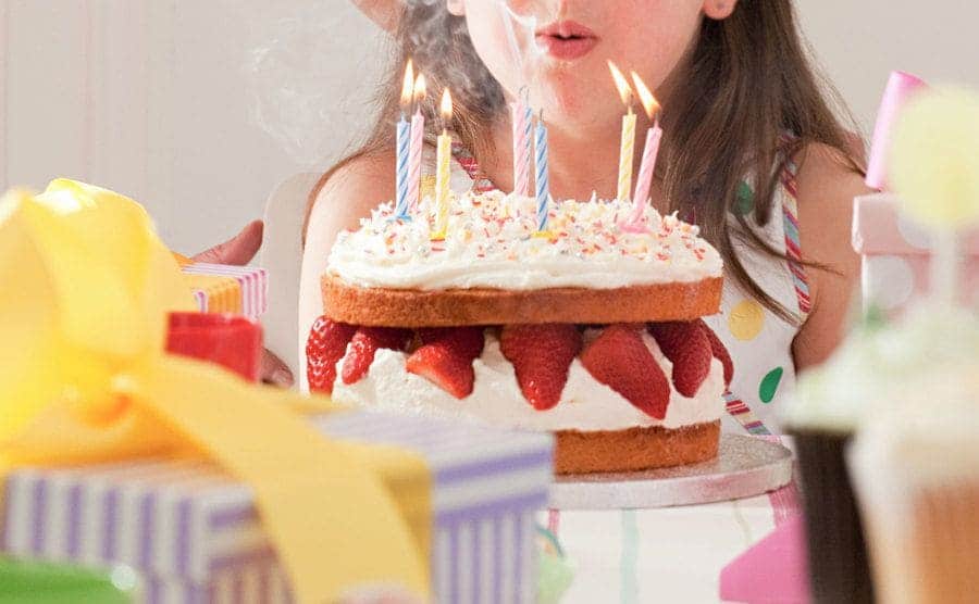 Little girl is blowing up the candles on her birthday cake.