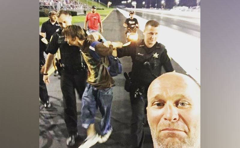 Joe Woods takes a photo while someone gets arrested during a race.