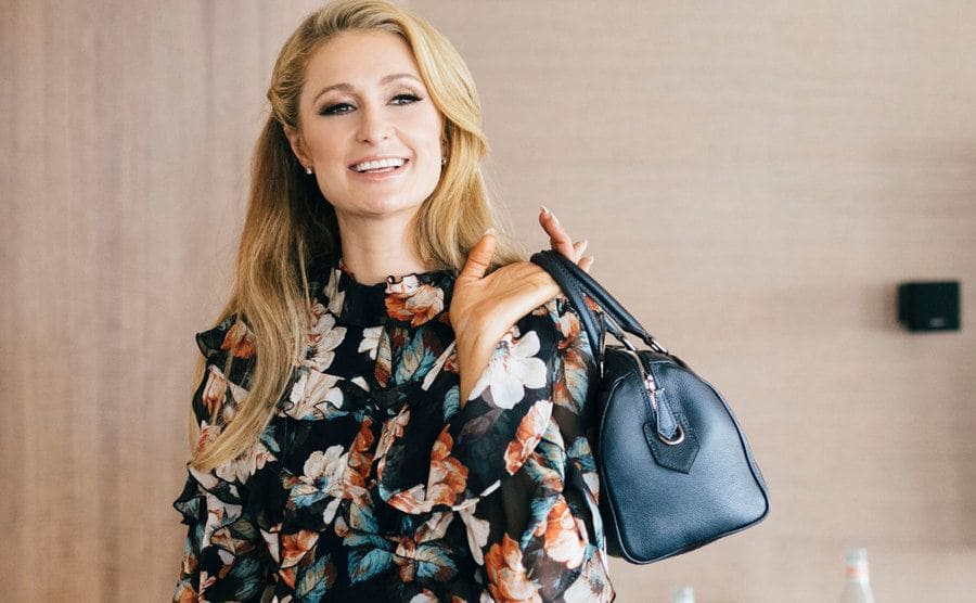Paris Hilton holding a handbag over her shoulder. 