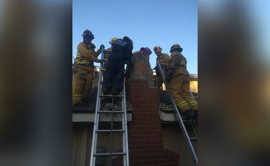 Firefighters help remove a man caught inside a chimney. 