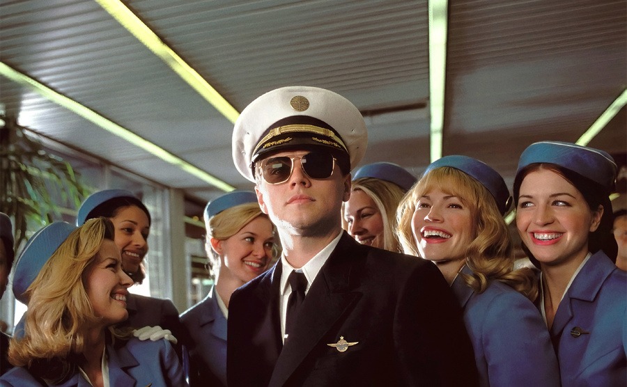 Leonardo DiCaprio is surrounded by flight stewardesses. 