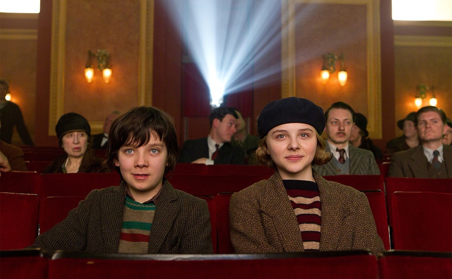 Asa Butterfield and Chloë Grace Moretz sit in a movie theater. 