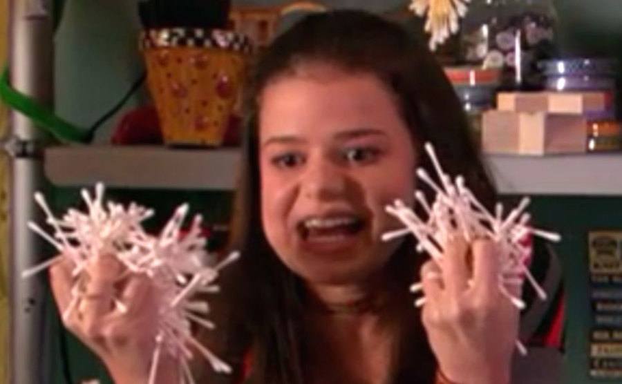 Abby Wilde as Stacy holds up hundreds of cotton swabs. 