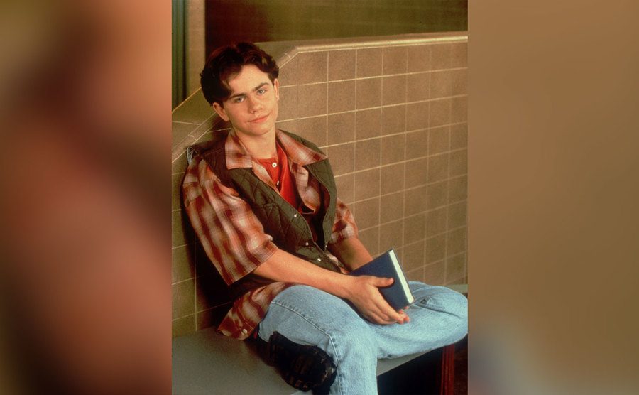 Rider Strong, as Shawn Hunter, sits in the school hallway. 