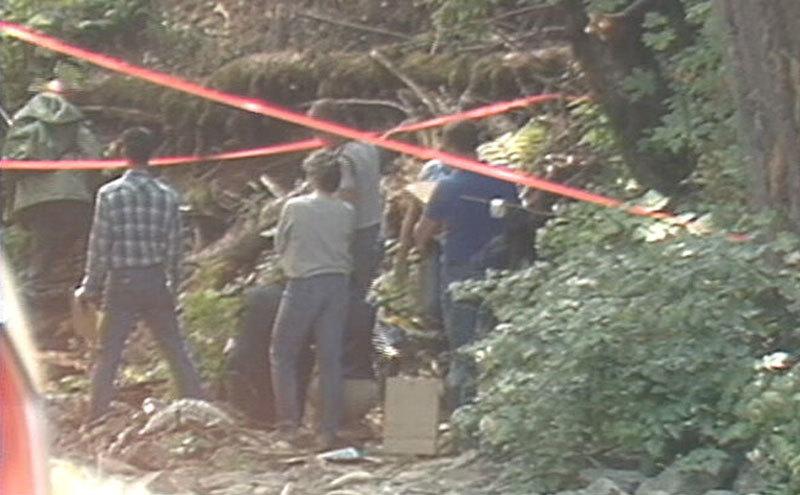 A dated photo of investigators searching the woods.