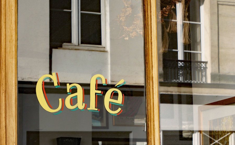 An image of the word Café painted in retro style on the window of a restaurant.