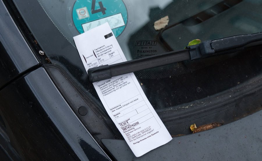 An image of a parking ticket stuck behind a windshield wiper.