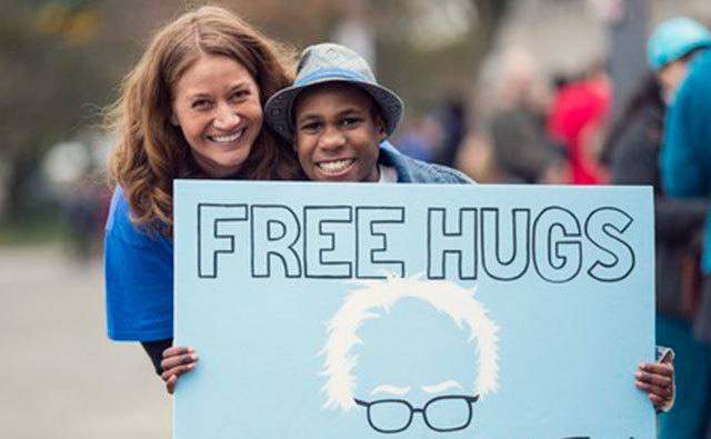 A picture of Jennifer and Devonte carrying a “free hugs” sign.