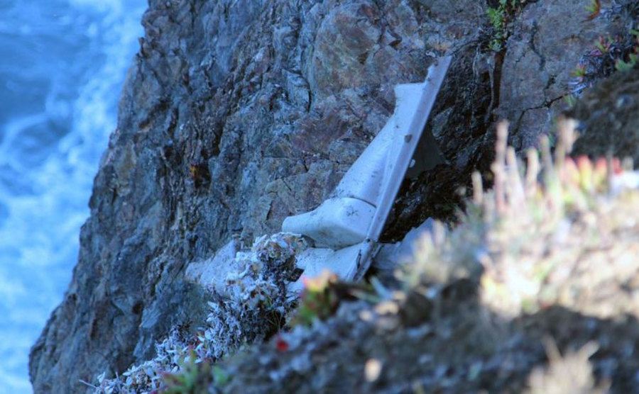 A photo of what appears to be a door panel lays discarded on the side of the cliff.