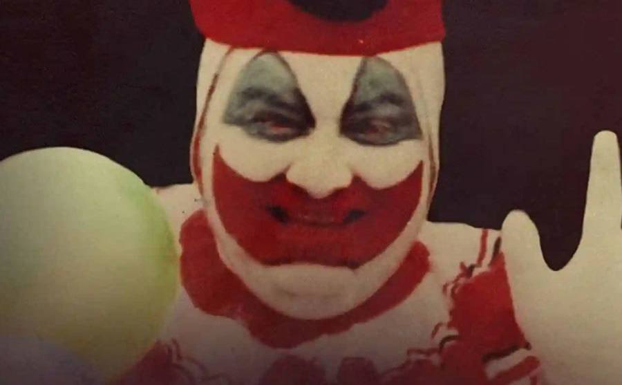 A photo of John Wayne Gacy wearing a clown costume.
