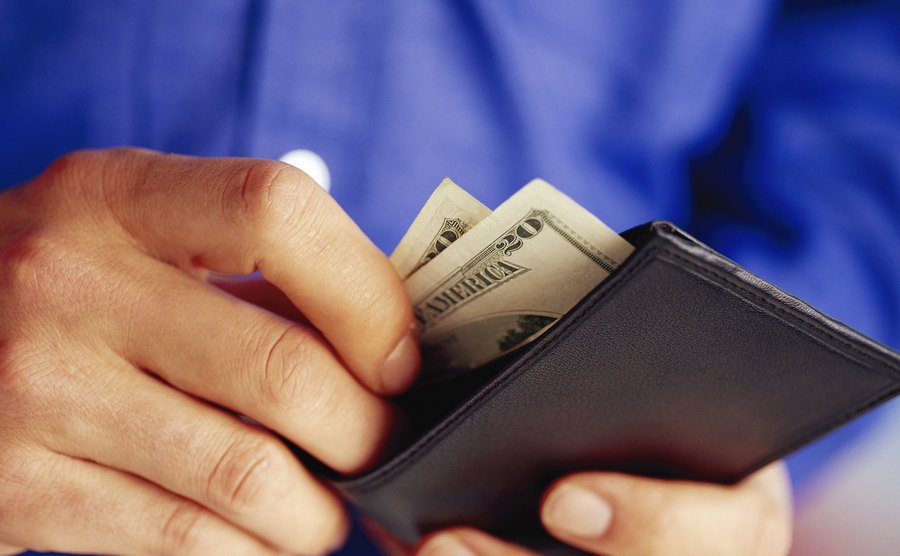 An image of male hands taking money from a wallet.