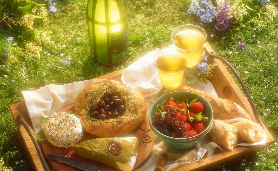 An image of a romantic picnic with wine, cheese, and red fruits.