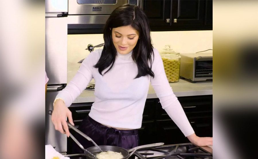 Kylie is cooking in the kitchen. 