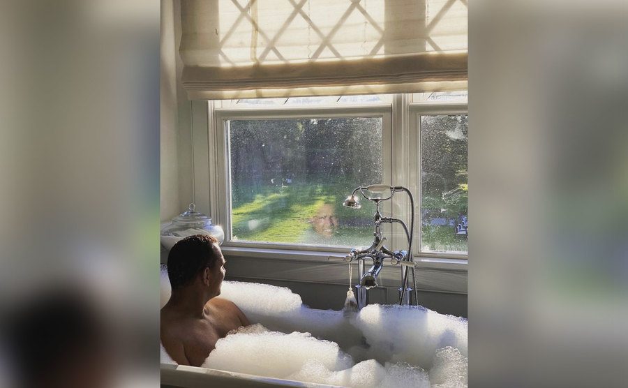Alex Rodriguez is relaxing in his bath and looking out the window. 