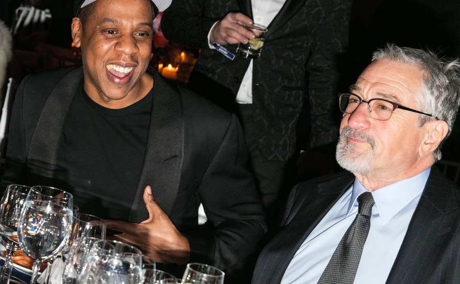 A picture of Jay Z and De Niro sitting together at an event.