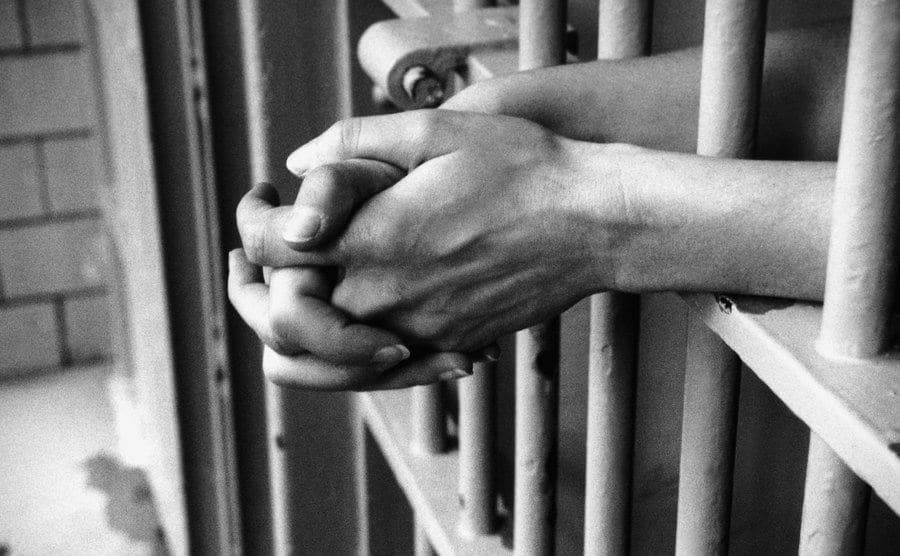 A photo of hands in a prison cell.