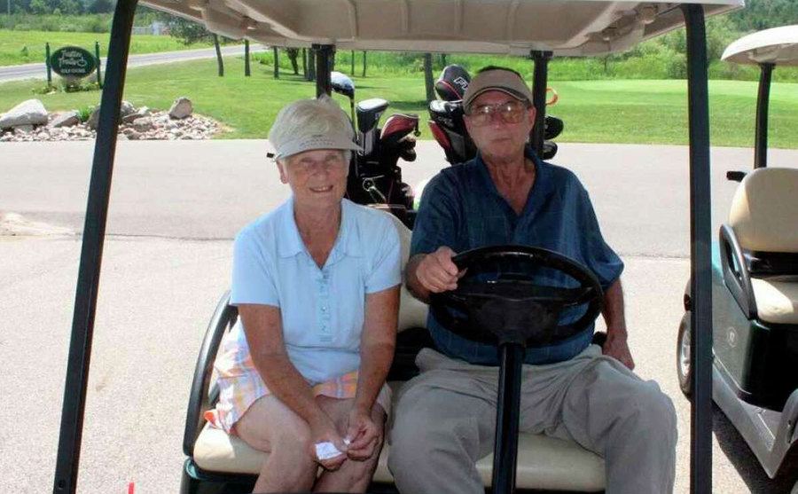 Marge and Jerry pose in a golf cart. 