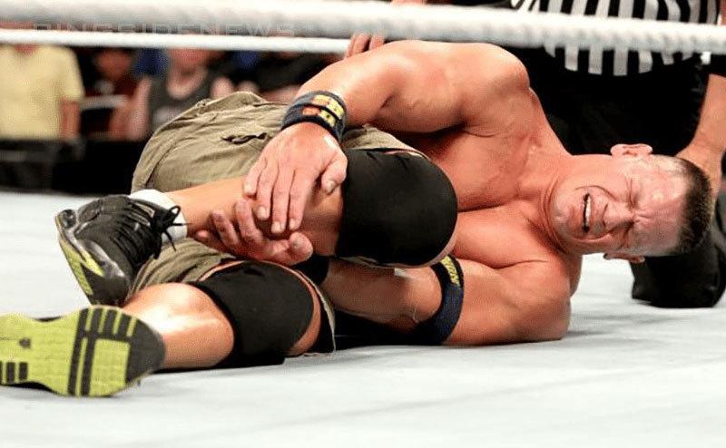 John Cena cries in pain on the floor of the ring. 