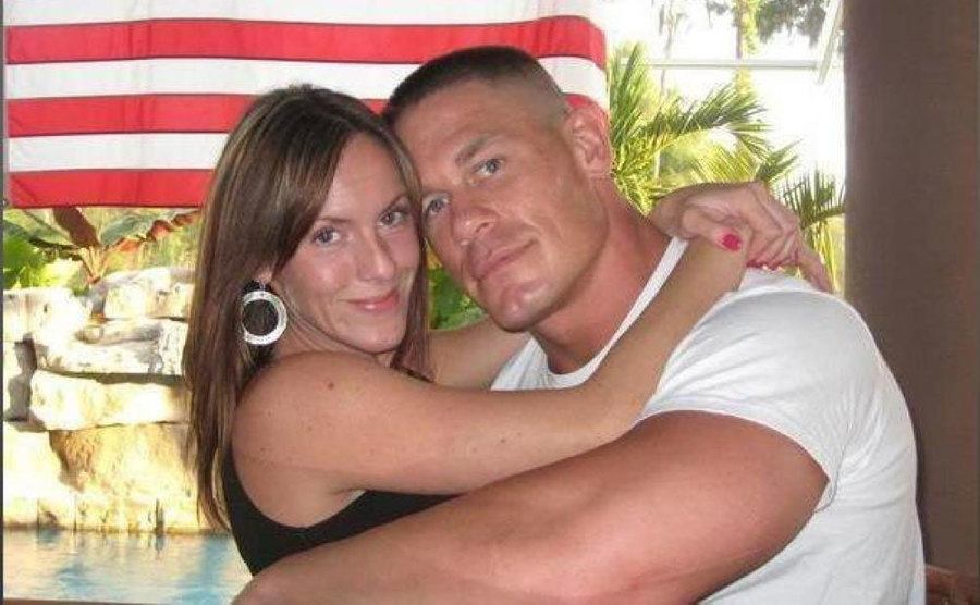 John Cena and Elizabeth Huberdeau embrace for a photo. 