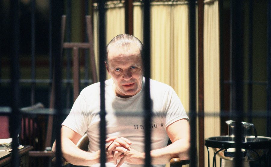 A still of Anthony Hopkins sitting behind bars in a Silence of the Lambs scene.