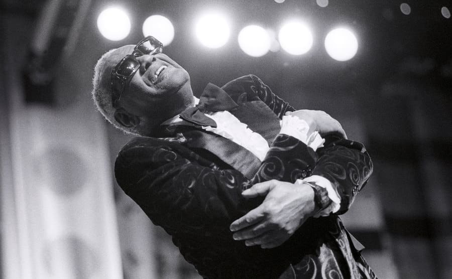 A dated image of Ray Charles performing on stage.