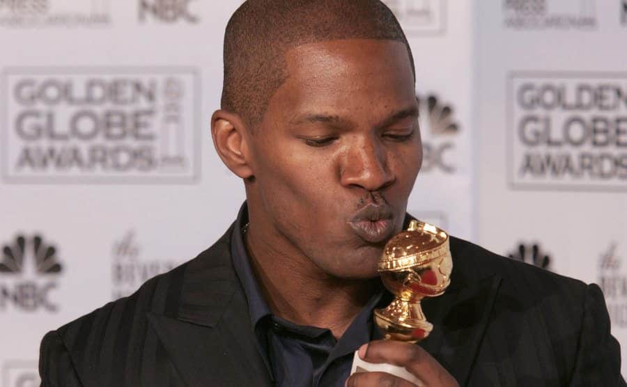 Foxx poses backstage, holding his award at the Golden Globes.