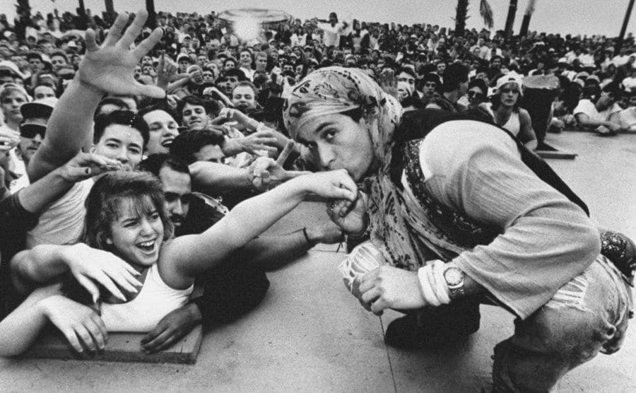 An image of Pauly crouching down to kiss the hand of a female fan.