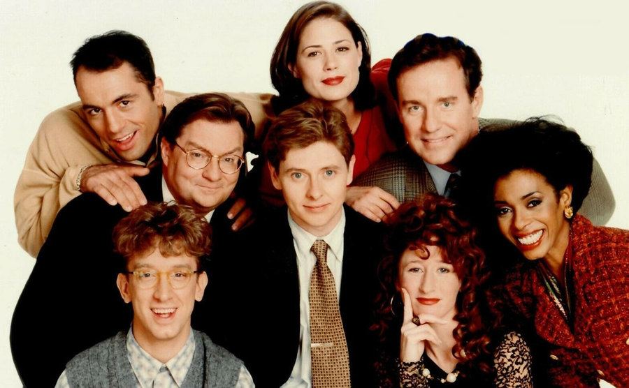 The cast of NewsRadio pose together. 