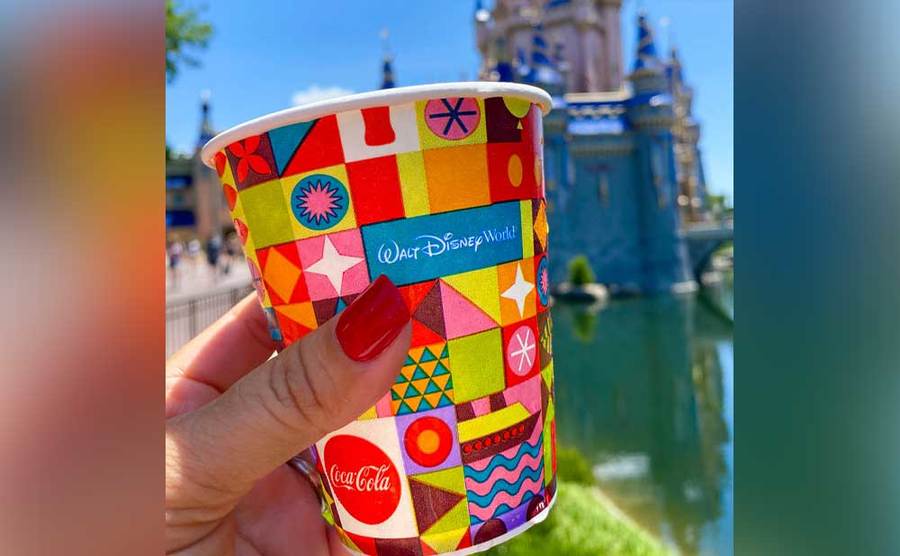 A woman holds up a paper cup at Disneyland. 