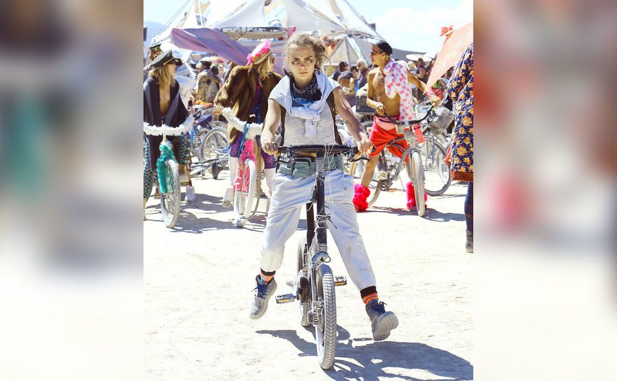 Cara Delevingne rides a bike during Burning Man. 